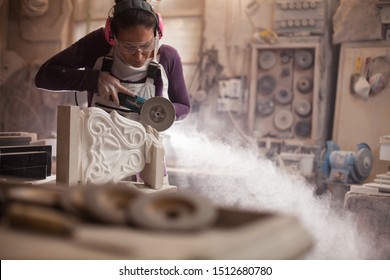 Female worker in an art workshop, grinding a piece of white marble, sculptor creating a stone sculpture, cloud of dust flying away, stonemasonry and stonecraft - Powered by Shutterstock