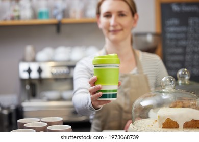 Female Worker in Cafe Serving Coffee In Sustainable Reusable Cup - Powered by Shutterstock