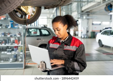 Female worker of car repair service in uniform using laptop in workshop to look for data in online sources, take new orders or consult clients - Powered by Shutterstock