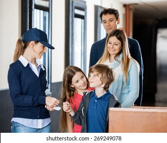 Female Worker Checking Movie Tickets Of Family At Cinema