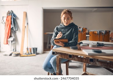 Female Worker In Concrete Workshop Using Digital Tablet And Stylus