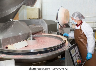 Female worker controlling process of making finely ground meat batter in bowl chopper for cooked sausage and frankfurters on meat factory - Powered by Shutterstock