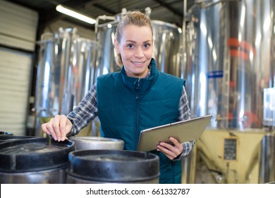 female worker holding digital tablet by barrels of beer - Powered by Shutterstock