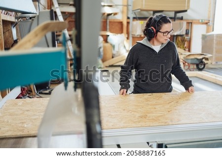 Female worker in an industrial woodworking factory working with a large sheet of chipboard or particle board in an employment or manufacturing concpet Stock foto © 