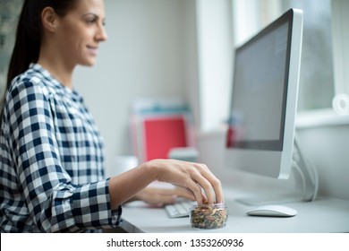 Female Worker In Office Having Healthy Snack Of Dried Nuts And Seeds