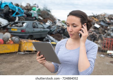 female worker phoning with clipboard at a metal scrap yard - Powered by Shutterstock