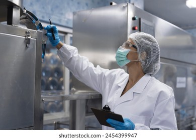 Female worker produces inspecting quality of plastic water tank on conveyor belt in drinking water factory. Worker using tablet working and checking bottle or gallon on conveyor production line - Powered by Shutterstock