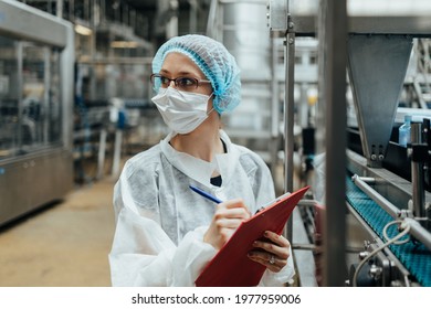 Female Worker With Protective Face Mask Working In Medical Supplies Research And Production Factory And Checking Canisters Of Distilled Water Before Shipment. Inspection Quality Control. 