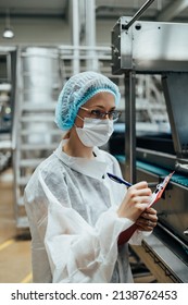 Female Worker With Protective Face Mask Working In Medical Supplies Research And Production Factory And Checking Canisters Of Distilled Water Before Shipment. Inspection Quality Control. 