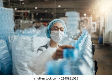 Female Worker With Protective Face Mask Working In Medical Supplies Research And Production Factory And Checking Canisters Of Distilled Water Before Shipment. Inspection Quality Control. 