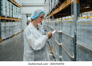 Female Worker In Protective Workwear Working In Medical Supplies Research And Production Factory And Checking Packed Canisters Of Distilled Water Before Shipment. Inspection Quality Control. 