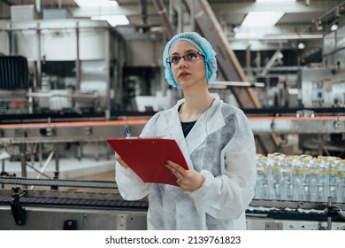 Female Worker In Protective Workwear Working In Medical Supplies Research And Production Factory And Checking Canisters Of Distilled Water Before Shipment. Inspection Quality Control. 