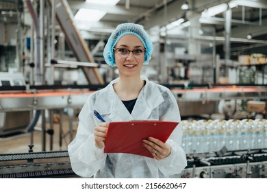 Female Worker In Protective Workwear Working In Medical Supplies Research And Production Factory And Checking Canisters Of Distilled Water Before Shipment. Inspection Quality Control. 