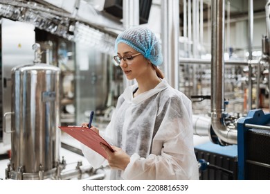 Female Worker In Protective Workwear Working In Medical Supplies Research And Production Factory And Checking Canisters Of Distilled Water Before Shipment. Inspection Quality Control. 