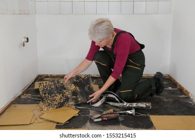 Female Worker Removing Old Vinyl Tiles From Kitchen Floor Using Spatula Trowel Tool