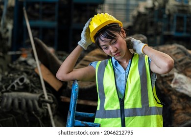 Female Worker In A Safety Suit And A Hard Hat Working At A Steel Mill Feels A Headache In A Warehouse. 