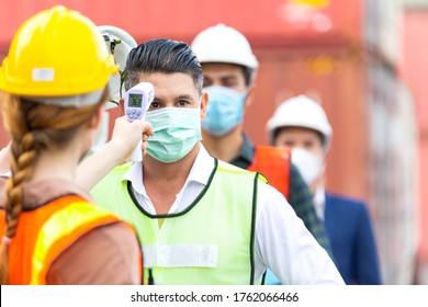 Female worker scanning fever temperature with digital thermometer to construction site staff wearing hygiene face mask protect from Coronavirus or COVID-19. New Normal working life adaptation