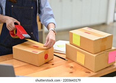 A Female Worker Or Small Business Owner Packing Her Shipping Box In Her Office Stock Room. E-commerce Business. Cropped Shot