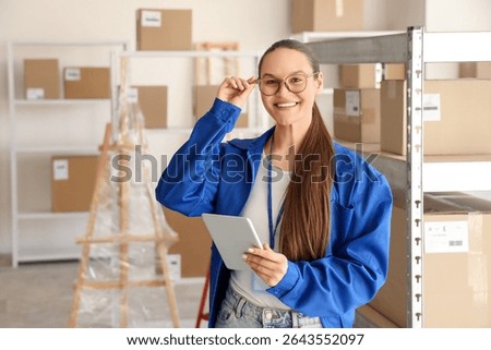 Female worker with tablet computer in warehouse