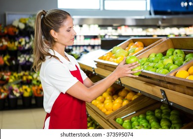 Female worker taking fruits in grocery store - Powered by Shutterstock