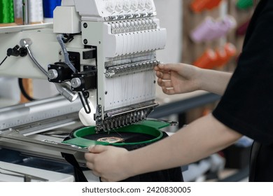 a female worker using and  preparing automatic tailoring machine for work  on clothing manufature factory - Powered by Shutterstock