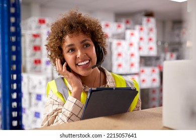 Female Worker Wearing Headset In Logistics Distribution Warehouse Using Digital Tablet