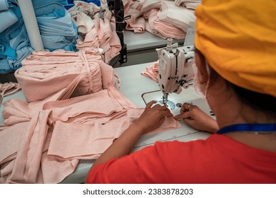 Female worker working in a garment factory in an industrial park in Ho Chi Minh City, Vietnam, with modern machinery and technology systems.