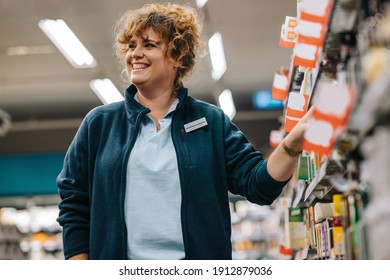 Female Worker Working In Store. Grocery Store Manager Standing In Aisle And Smiling.