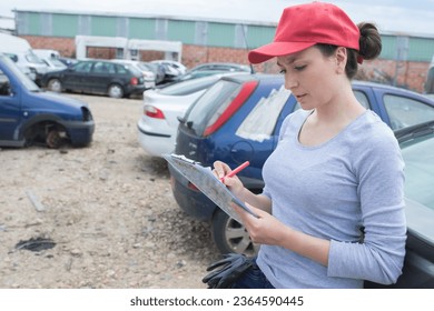 female working on car scrap yard - Powered by Shutterstock