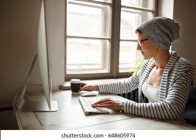 Female working on computer and drinking coffee at workplace