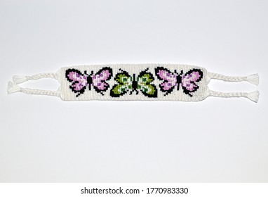 Female woven friendship bracelet with alpha pattern 
butterflies handmade of thread on white background