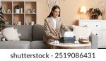 Female writer with typewriter sitting on sofa at home