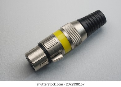 Female XLR jack without cable, metallic material with yellow strip, isolated on white background, closeup macro shots