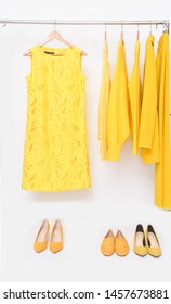 Female Yellow Dress Clothes With ,yellow Shorts Sweater ,shirt And Skirt ,coat With Three Pair Shoes Isolated On Hanger
