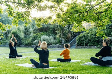 Female yoga class in park. Group of diverse women doing stretching pose exercising together with instructor on green grass lawn. Sport activity for health, wellbeing, mental health. Selective focus - Powered by Shutterstock