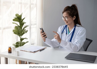 Female Young Asian doctor making video call with patient by smartphone cell phone laptop tablet   - Powered by Shutterstock