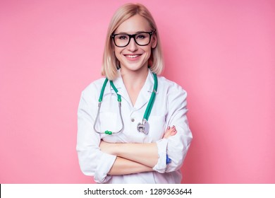 Female Young And Beautiful Blond Woman Veterinary Doctor Using Stethoscope In A White Medical Coat On A Pink Background In The Studio