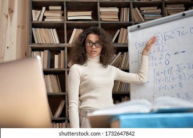 Female Young Hispanic University Teacher, College Tutor Explaining Math Giving Remote School Class Online Lesson Teaching Looking At Laptop In Classroom By Elearning Webcam Video Conference Zoom Call.