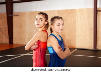 Female youth wrestling teammates in blue and red singlets