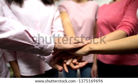Females with cancer in pink shirts putting hands together, support, feminism
