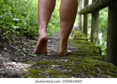 female's feet that are dirty, walking barefoot in a mossy pathway in a public park - Powered by Shutterstock