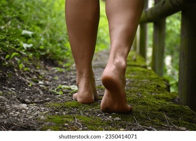 female's feet that are dirty, walking barefoot in a mossy pathway in a public park - Powered by Shutterstock