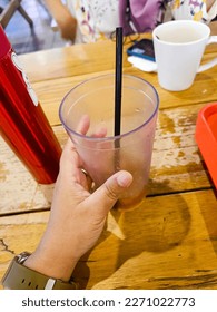 Female's hand holding an empty glass of icedtea.