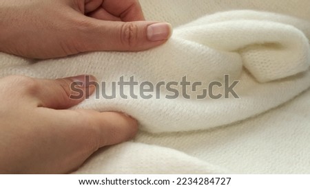 female's hand on the fabric of white plush cloth with soft nap. Clothing industry concept, slow motion. woman checking the quality of clothes, enjoys the soft pleasant texture of the fabric