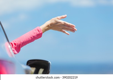Female's hand outside her car window feeling the ocean breeze. (Vacation and Getaway concept)