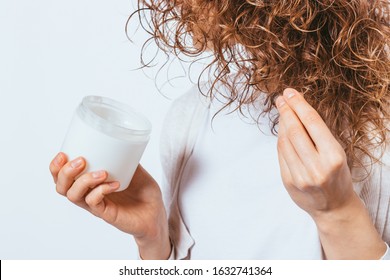 Female's Hands Apply Cosmetic Coconut Oil On Her Curly Hair Tips, Close-up.