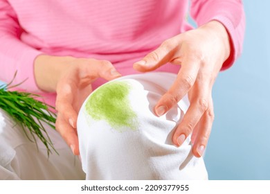 Female's Hands Showing Dirty Grass Stain On White Clothes.on A Blue Background. Isolated.High Quality Photo