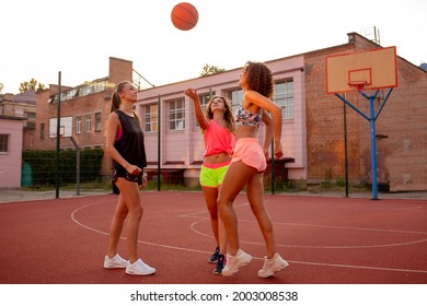 Females playing basketball on street court, on summer day. Female street basketball player in action - Powered by Shutterstock