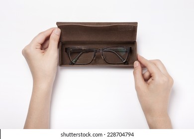 A Female(woman, Girl) Hold A Leather Eye Wear(glasses) Case With Glasses Isolated White, Top View.