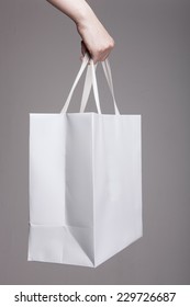 A Female(woman) Hand Hold A White Shopping Bag(paper Bag) And White Strings At The Studio.